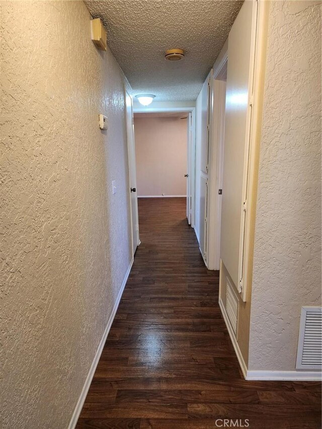 2120 Jacaranda Ct, San Bernardino, CA 92404 - hall featuring a textured wall, dark wood-type flooring, a textured ceiling, and baseboards