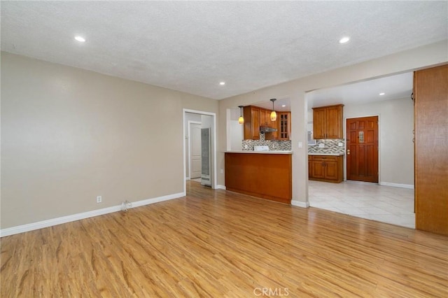 unfurnished living room with light wood-style floors, a textured ceiling, baseboards, and recessed lighting