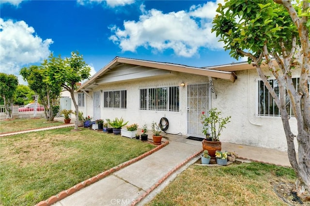 bungalow with stucco siding and a front lawn