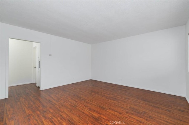 spare room featuring wood finished floors and baseboards