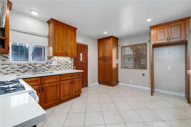 kitchen with a sink, brown cabinets, tasteful backsplash, light countertops, and recessed lighting