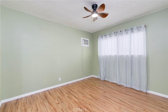 empty room featuring light wood-type flooring, baseboards, ceiling fan, and a textured ceiling