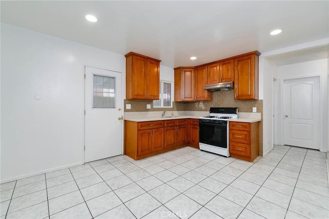 kitchen featuring gas range gas stove, light countertops, a sink, brown cabinetry, and recessed lighting
