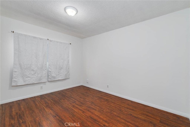 empty room featuring wood finished floors, baseboards, and a textured ceiling