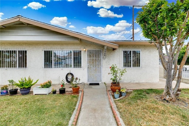 bungalow with stucco siding and a front yard