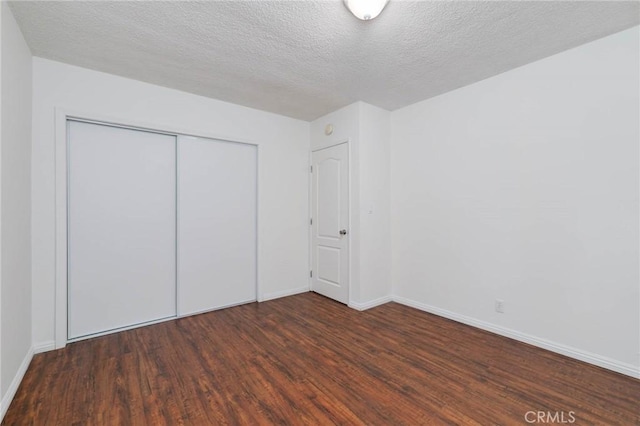 unfurnished bedroom with wood finished floors, baseboards, a closet, and a textured ceiling