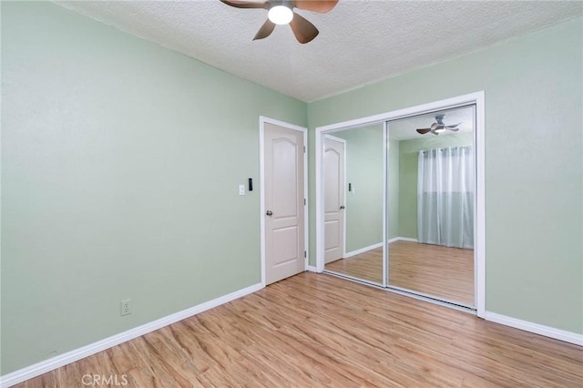 unfurnished bedroom featuring light wood-style flooring, baseboards, a textured ceiling, a closet, and ceiling fan