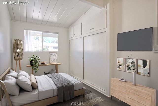 bedroom with dark wood-style flooring, lofted ceiling, a closet, and wooden ceiling