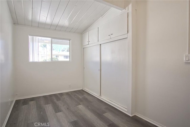 unfurnished bedroom featuring dark wood finished floors, a closet, baseboards, wooden ceiling, and lofted ceiling