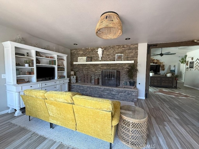 17857 Main St, Hesperia, CA 92345 - living room with a stone fireplace, a ceiling fan, wood finished floors, and baseboards