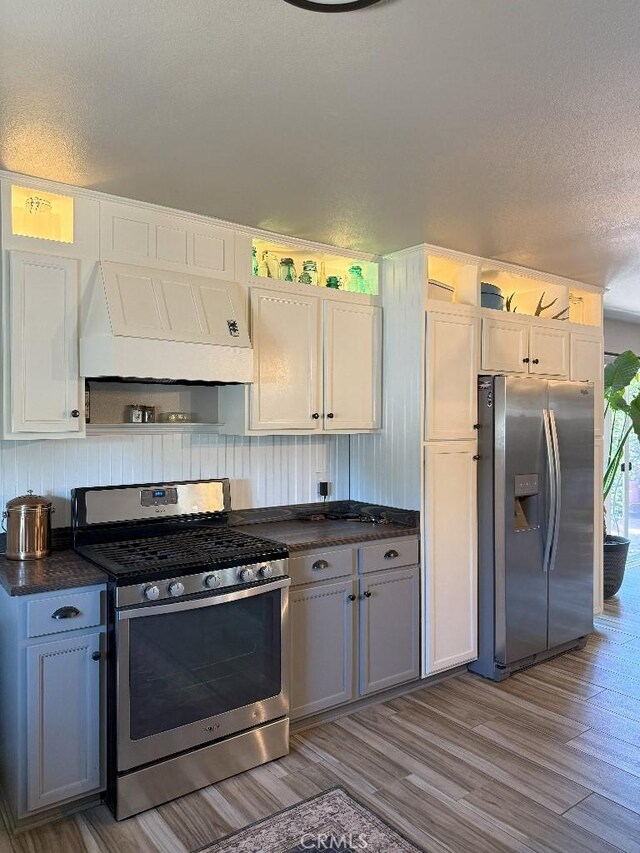 17857 Main St, Hesperia, CA 92345 - kitchen featuring stainless steel appliances, custom exhaust hood, dark countertops, wood finished floors, and a textured ceiling