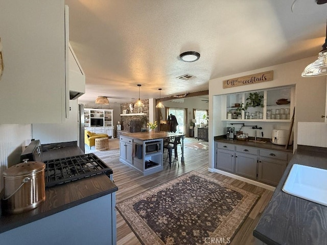 17857 Main St, Hesperia, CA 92345 - kitchen with butcher block counters, light wood-type flooring, hanging light fixtures, stainless steel microwave, and a sink