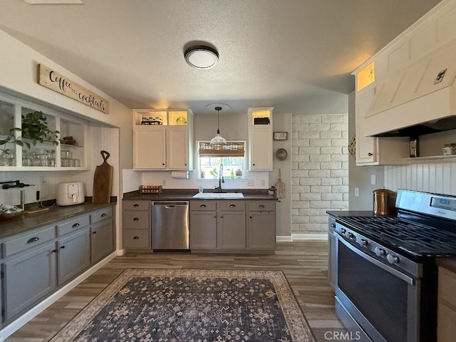 17857 Main St, Hesperia, CA 92345 - kitchen with stainless steel appliances, a sink, dark countertops, dark wood-type flooring, and decorative light fixtures