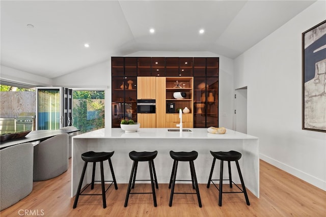 1318 Outrigger Dr, Corona Del Mar, CA 92625 - kitchen with a sink, vaulted ceiling, stainless steel oven, a kitchen bar, and light wood-type flooring