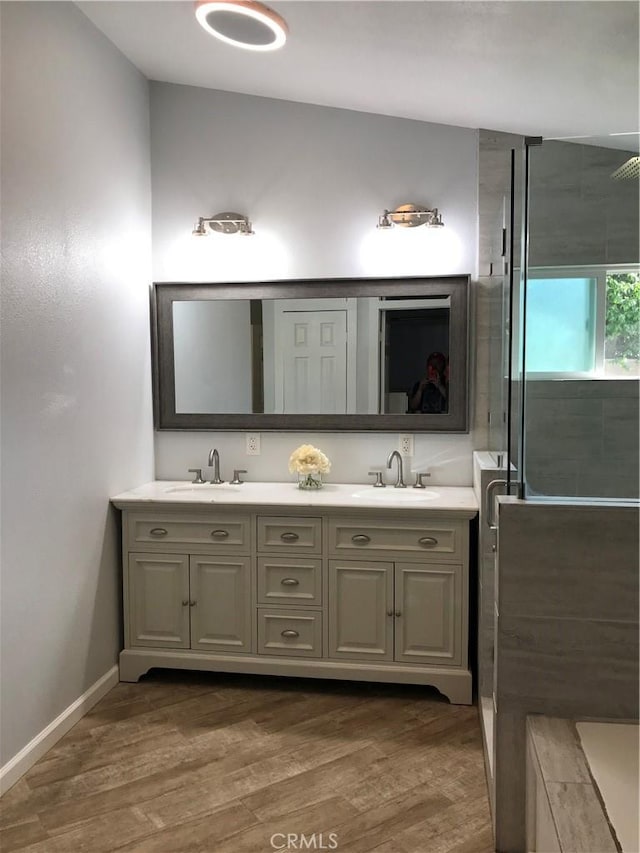 26021 Crestmont Cir, Menifee, CA 92586 - bathroom featuring wood finished floors, double vanity, a tile shower, and baseboards