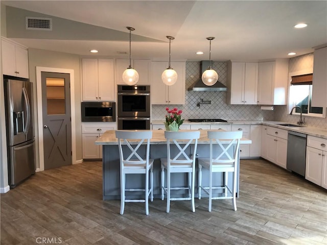26021 Crestmont Cir, Menifee, CA 92586 - kitchen with stainless steel appliances, tasteful backsplash, white cabinets, wall chimney exhaust hood, and a kitchen island