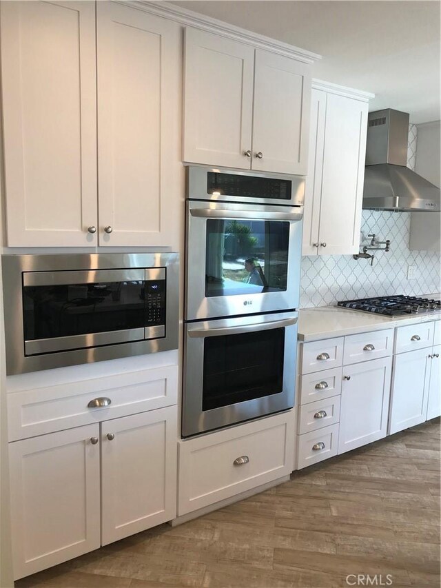 26021 Crestmont Cir, Menifee, CA 92586 - kitchen featuring stainless steel appliances, wall chimney exhaust hood, light countertops, and white cabinets