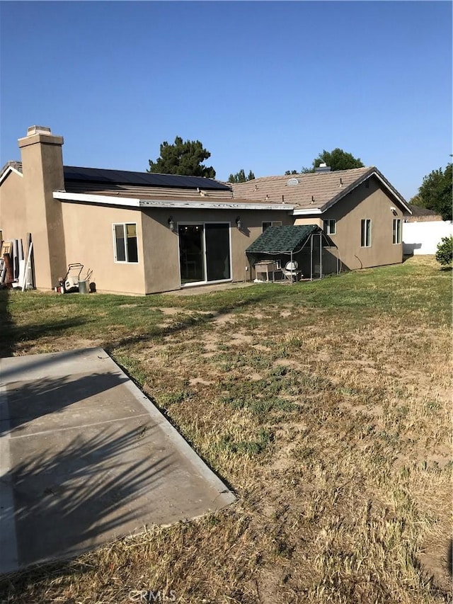 26021 Crestmont Cir, Menifee, CA 92586 - rear view of house featuring solar panels, a yard, a chimney, and stucco siding