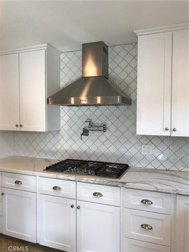 26021 Crestmont Cir, Menifee, CA 92586 - kitchen featuring wall chimney range hood, stainless steel gas cooktop, backsplash, white cabinetry, and light stone counters