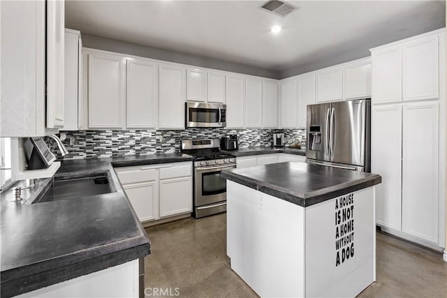 7311 Pinewood Ct, Eastvale, CA 92880 - kitchen featuring stainless steel appliances, dark countertops, backsplash, white cabinetry, and finished concrete floors