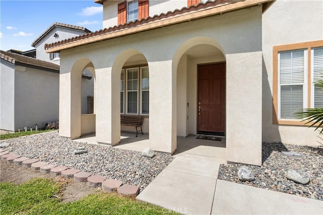 7311 Pinewood Ct, Eastvale, CA 92880 - view of exterior entry with stucco siding, a porch, and a tiled roof
