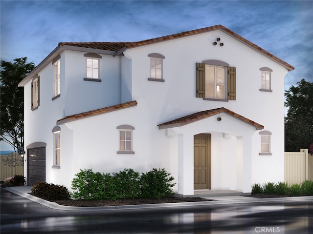 mediterranean / spanish-style house featuring a tiled roof, an attached garage, and stucco siding
