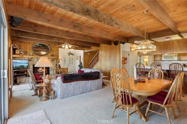 24571 Albrun Dr, Crestline, CA 92325 - carpeted dining space featuring wood ceiling with exposed beams, wood walls, a chandelier, a ceiling fan, and stairs