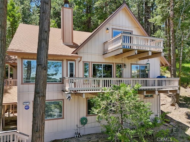 24571 Albrun Dr, Crestline, CA 92325 - back of property featuring a balcony, a shingled roof, and a chimney