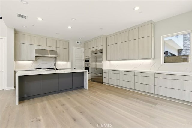 208 Stage, Irvine, CA 92618 - kitchen featuring stainless steel built in refrigerator, under cabinet range hood, modern cabinets, light wood-type flooring, and tasteful backsplash