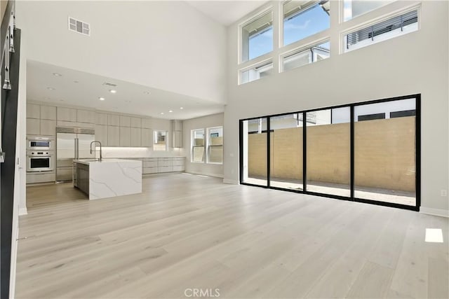208 Stage, Irvine, CA 92618 - unfurnished living room featuring light wood-style flooring, a high ceiling, and recessed lighting