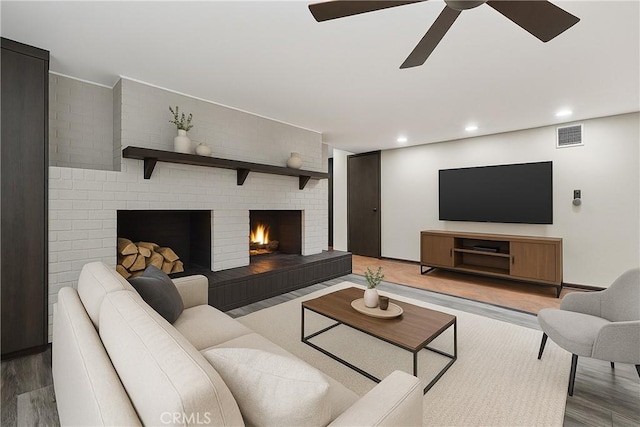living room featuring wood finished floors, a brick fireplace, a ceiling fan, and recessed lighting