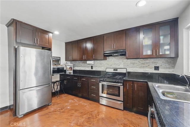 kitchen with appliances with stainless steel finishes, under cabinet range hood, a sink, dark brown cabinets, and tasteful backsplash