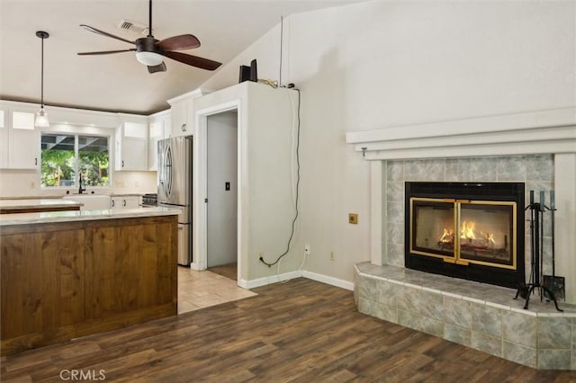 8825 Old Santa Rosa Rd, Atascadero, CA 93422 - kitchen featuring freestanding refrigerator, dark wood-style flooring, white cabinets, ceiling fan, and a tiled fireplace