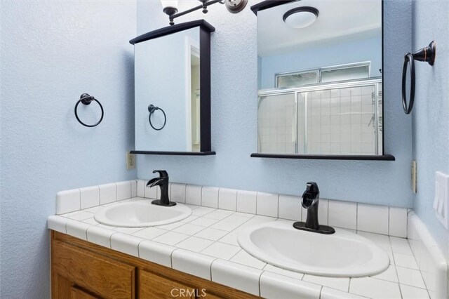 8825 Old Santa Rosa Rd, Atascadero, CA 93422 - full bathroom featuring double vanity, a textured wall, and a shower with shower door