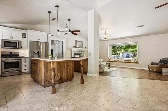 8825 Old Santa Rosa Rd, Atascadero, CA 93422 - kitchen featuring stainless steel appliances, open floor plan, ceiling fan, lofted ceiling, and a tile fireplace