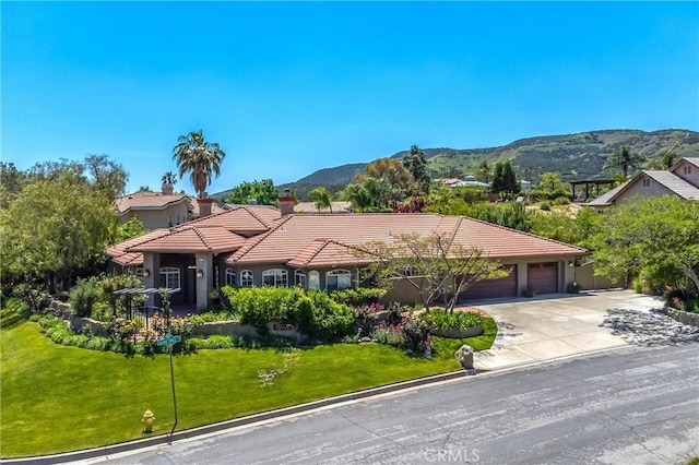 34879 Olive Tree Ln, Yucaipa, CA 92399 - view of front of home with a tile roof, a garage, a front lawn, concrete driveway, and a mountain view