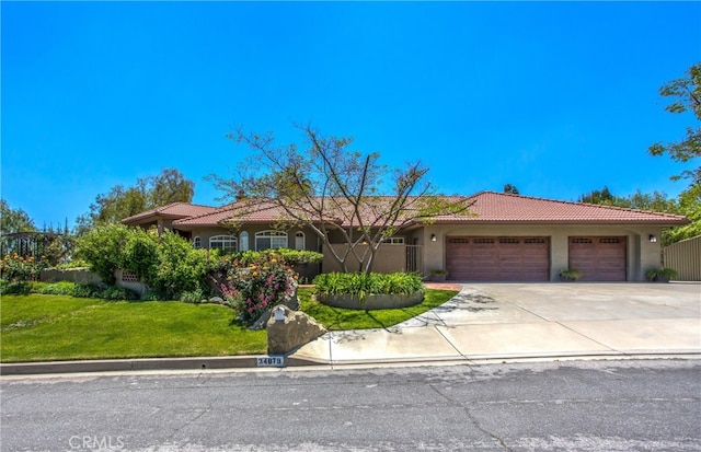 34879 Olive Tree Ln, Yucaipa, CA 92399 - view of front facade with a tile roof, an attached garage, stucco siding, a front yard, and driveway
