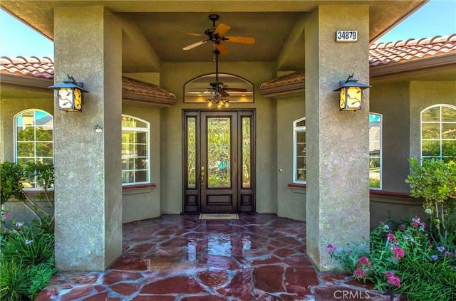 34879 Olive Tree Ln, Yucaipa, CA 92399 - view of exterior entry with a tiled roof, a ceiling fan, and stucco siding