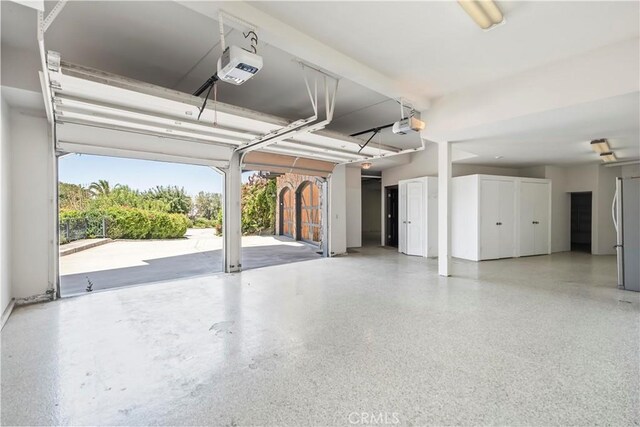 7008 Hawarden Dr, Riverside, CA 92506 - garage featuring a garage door opener and freestanding refrigerator