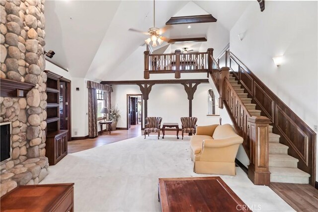 7008 Hawarden Dr, Riverside, CA 92506 - living area featuring high vaulted ceiling, ceiling fan, stairs, a fireplace, and wood finished floors