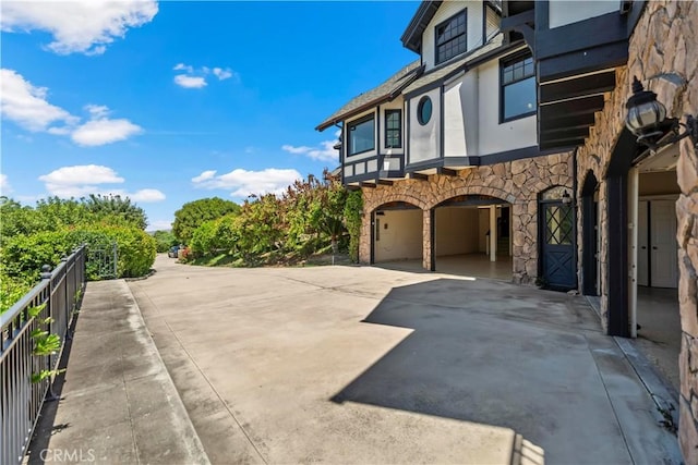 7008 Hawarden Dr, Riverside, CA 92506 - view of side of property with stone siding, a garage, driveway, and fence