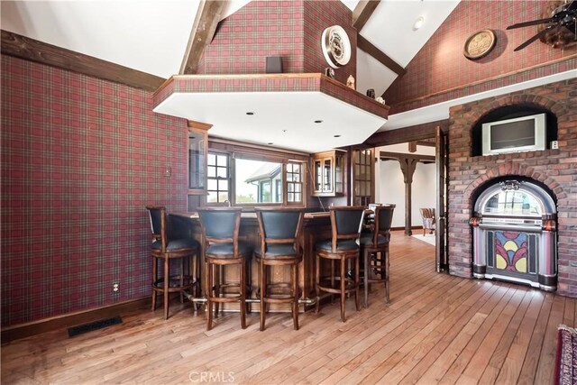 7008 Hawarden Dr, Riverside, CA 92506 - dining area with a dry bar, wood-type flooring, high vaulted ceiling, healthy amount of natural light, and wallpapered walls