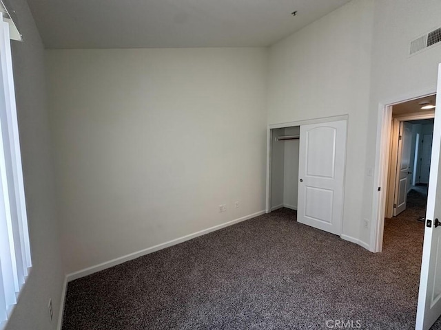 unfurnished bedroom featuring carpet, baseboards, high vaulted ceiling, and a closet