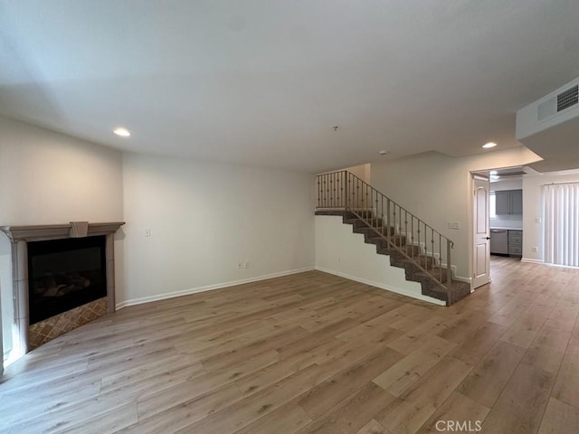 unfurnished living room featuring light wood-type flooring, stairs, recessed lighting, baseboards, and a fireplace