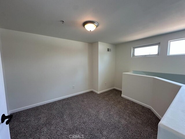 carpeted spare room with baseboards and a pendent fire sprinkler
