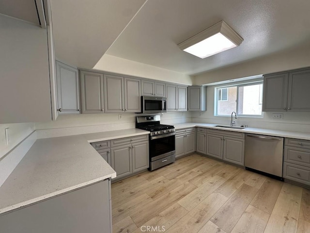 kitchen featuring gray cabinetry, appliances with stainless steel finishes, and a sink