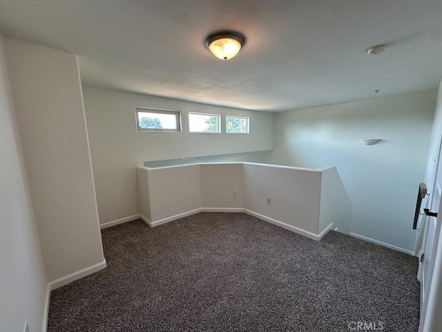carpeted spare room featuring baseboards and a smoke detector