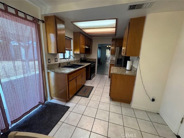 13278 Parkland Cir, Sylmar, CA 91342 - kitchen featuring range, a sink, light tile patterned flooring, brown cabinetry, and stainless steel fridge