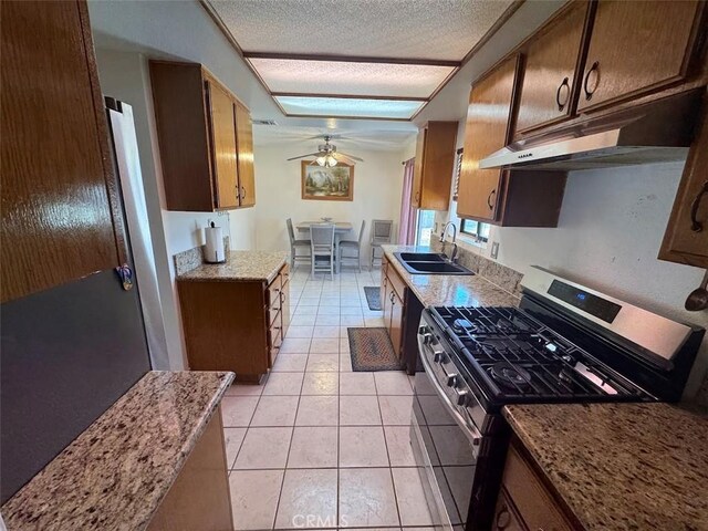13278 Parkland Cir, Sylmar, CA 91342 - kitchen with stainless steel gas range oven, a sink, under cabinet range hood, ceiling fan, and light tile patterned floors