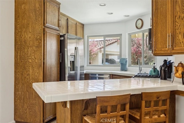 1334 Tourney Hill Ln Unit 61, Nipomo, CA 93444 - kitchen with appliances with stainless steel finishes, a peninsula, a kitchen breakfast bar, brown cabinets, and recessed lighting
